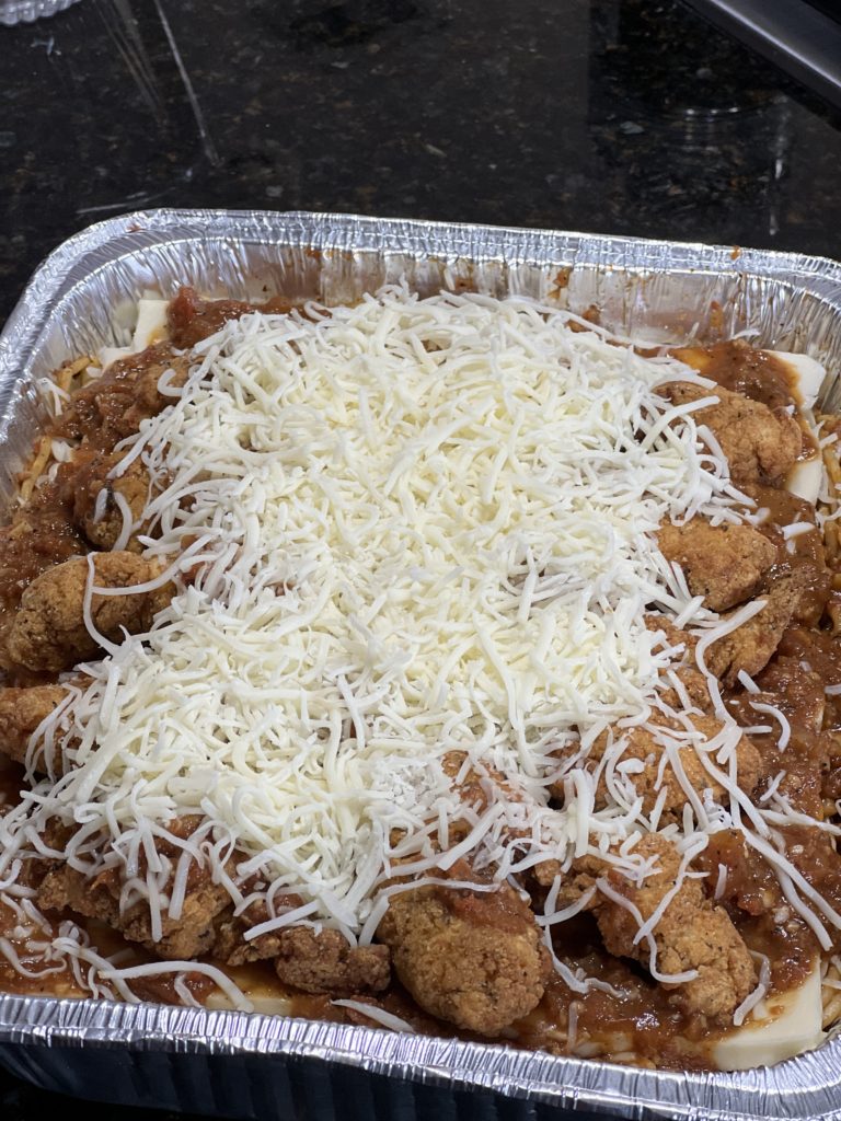 chicken on top of a baked spaghetti with parmesan cheese on top
